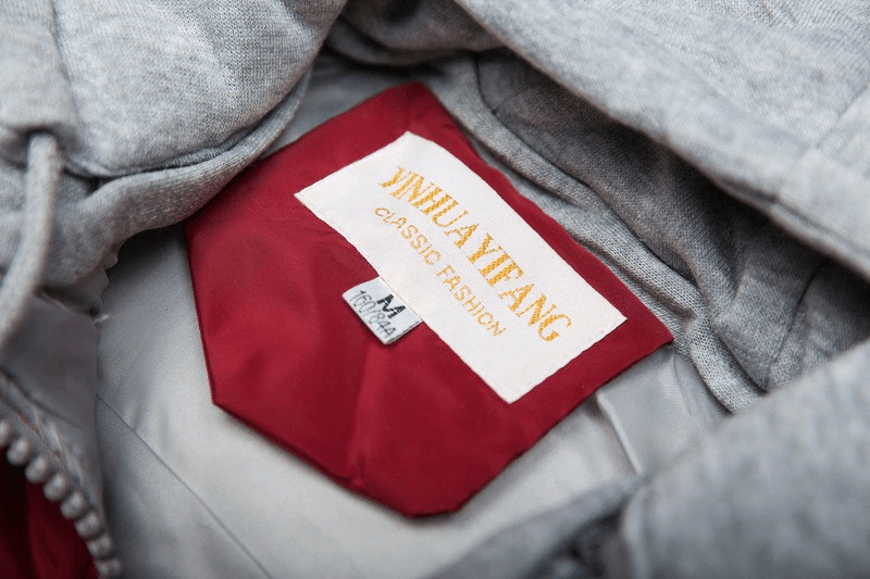 Close-up of a gray women's vest interior with a red label featuring 'YinHuaYiFang' text, showcasing classic fashion design details.